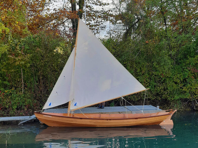 CLC Northeaster Dory at the dock with its sails up.