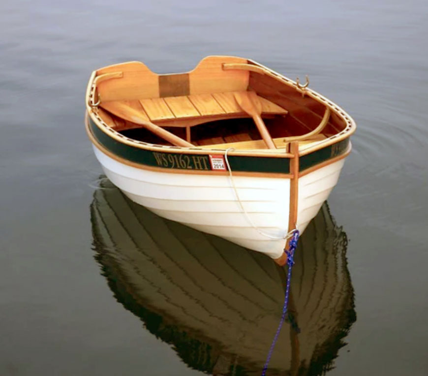 White wooden rowboat moored in the water.