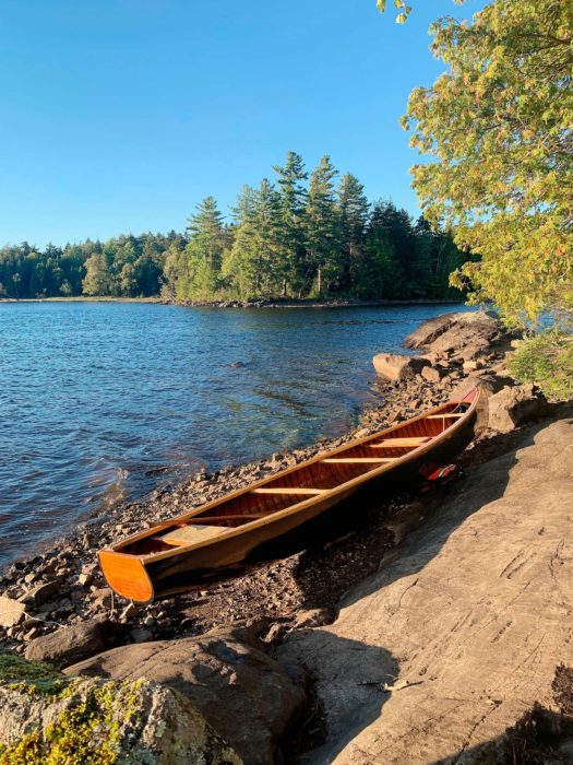 Picture of a wooden canoe ashore with Umbagog Lake in the background.